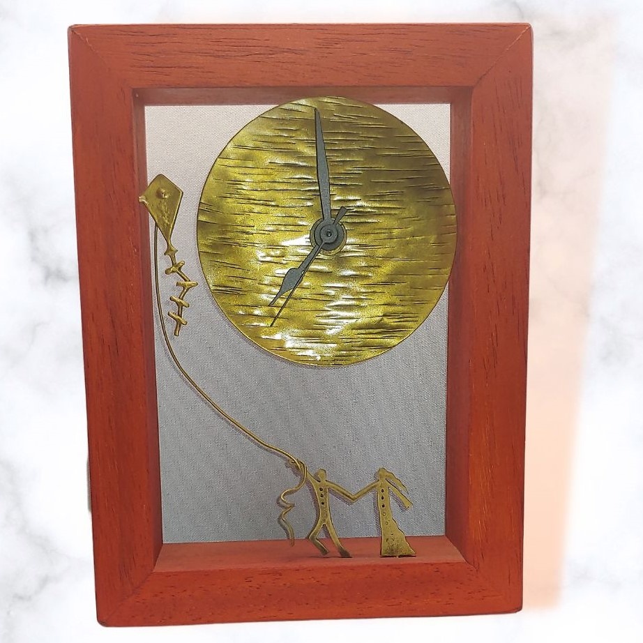 Bronze sculpture in frame with clock 